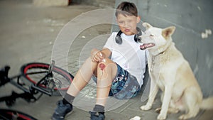 The boy sits in the park after falling off a bicycle, calms the pain in his knee, represents a dangerous bike riding