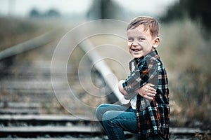 A boy sits on the railway tracks. Children's aggression. The child ran away from home.