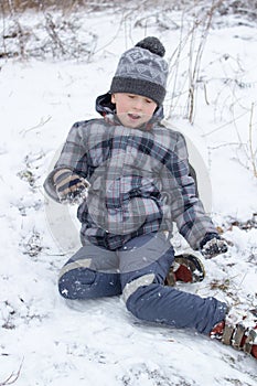 Boy sits in the snow,boy is afraid to go down the hill in winter with his eyes closed