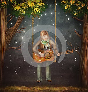 The boy sits on the swing in the forest and plays on guitar photo