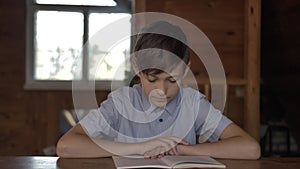 Boy sits at the table and reads a book, countyside