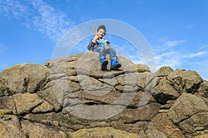 Boy sits on the top of a big rock