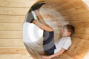 Boy sits in a wooden tunnel. Children`s eco playground