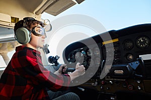 Boy sitting in airpalne cabin in headset, pretending he is a pilot