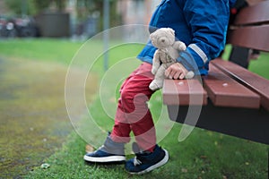 Boy sitting alone in a park with hie teddy bear