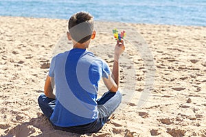 Boy sitting on the beach, looking to the sea ocean and holding colorful autism awareness heart