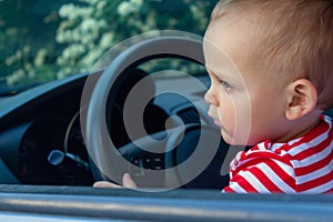 Boy sitting behind car wheel. Safety concept.