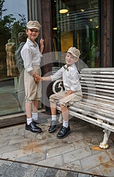 Boy sitting on a bench and holding the hand of his brother surrounded by buildings