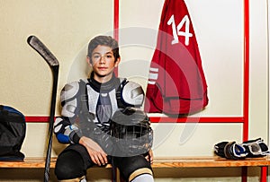 Boy sitting on the bench in ice hockey locker room