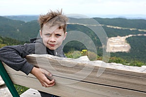 Boy sitting on bench on Lago-Naki plateau