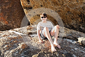 A boy sitting on a boulder