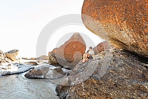 A boy sitting on a boulder at the beach