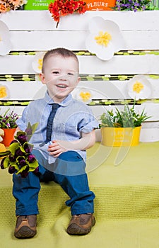 Boy sitting with a bouquet of flowers in a denim suit