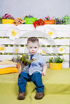 Boy sitting with a bouquet of flowers in a denim suit