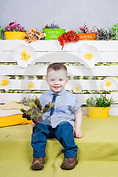 Boy sitting with a bouquet of flowers in a denim suit