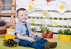 Boy sitting with a bouquet of flowers in a denim suit