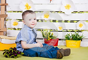 Boy sitting with a bouquet of flowers in a denim suit