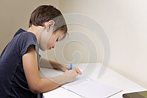 Boy sitting at the desk home and doing his homework. Child writting. School, children, education concept