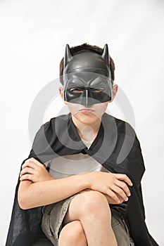 Boy sitting down and wearing a Batman mask