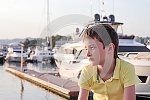 A boy is sitting on an embankment of a resort city, he is upset because all theatres and museums are closed or let