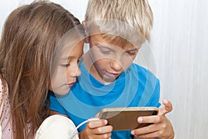 boy is sitting on floor and playing mobile games on his phone. girl sits next to him and worries about the process of playing