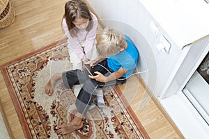 boy is sitting on floor and playing mobile games on his phone. girl sits next to him and worries about process of playing friend