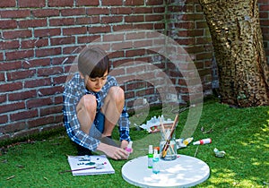 A boy doing artwork alone in the garden