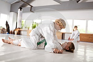 Boy sitting on girl after winning aikido fight with her