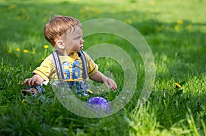 A boy sitting on the grass with a ball