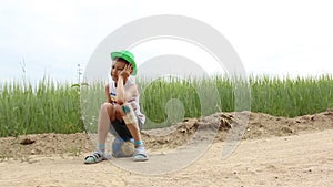 Boy sitting on the ground with a graze on knee filled with green paint