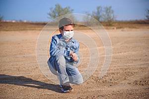 Boy is sitting on the ground in protective mask