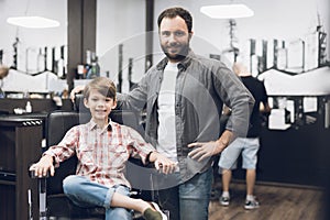 The boy is sitting in the hairdresser`s barber shop.