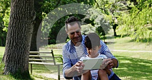 Boy sitting on his fathers lap and using digital tablet