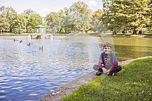 Boy sitting by lake in Boston public garden with geese