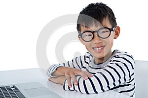 Boy sitting with laptop against white background