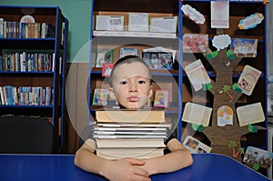 Boy sitting in library, putting head on pile of book