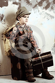 Boy sitting on luggage with books, retro shot, 50s-60s