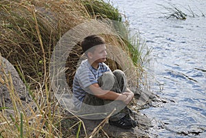 Boy sitting near the river