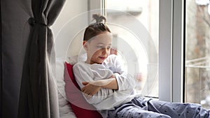 Boy sitting near on window sill measure the temperature