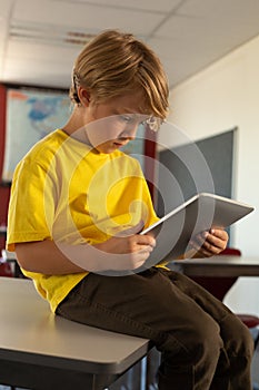 Boy sitting over desk and using digital tablet in a classroom