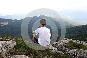 Boy sitting on rock on Lago-Naki plateau in summer