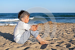 Boy sitting on sand at beach