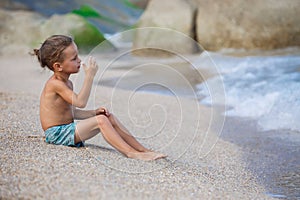 Boy sitting on the sand by the sea