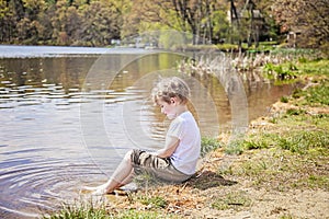 Boy sitting on shore of lake