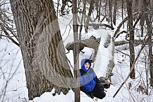 Boy Sitting in Snow Covered Forest