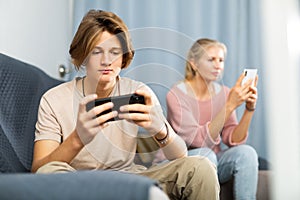 Boy sitting on sofa at home with smartphone