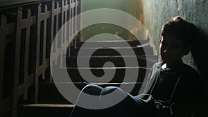 The boy is sitting on the steps of an abandoned porch. The concept of children`s drug addiction, vagrancy, homelessness