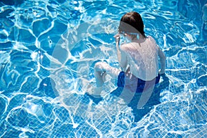 Boy sitting on the steps of a swimming pool