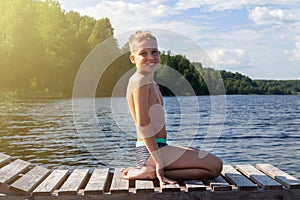 Boy sitting on sun lounger on lake