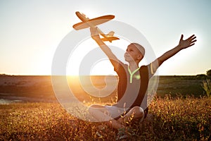 boy sitting at sunset with an airplane in his hand